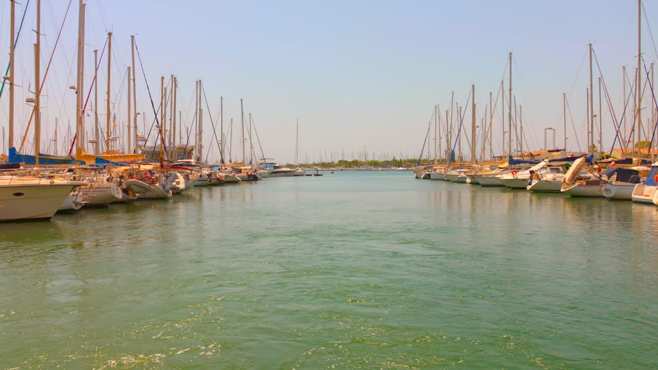 Peaceful view of Cap d'Agde's large marina, with rows of sailboats docked under clear skies