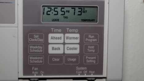 close up of thermostat while turning up the heat during winter