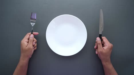 Empty plate with fork and knife on grey background