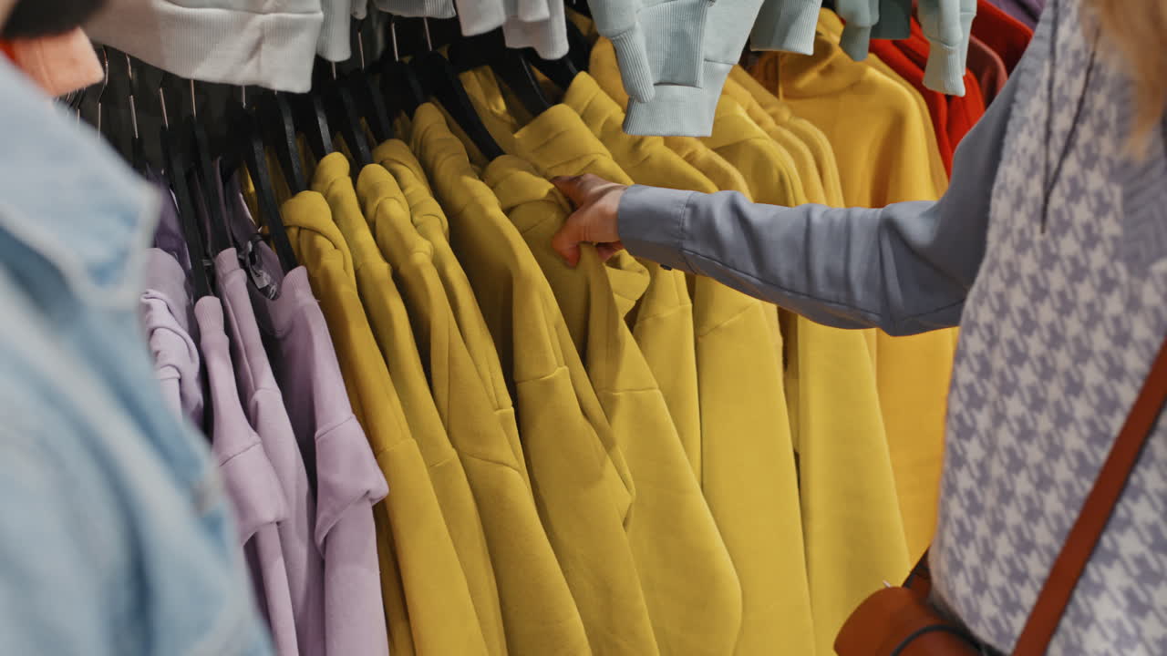 Couple Sorting Clothes On Rail In Clothing Store