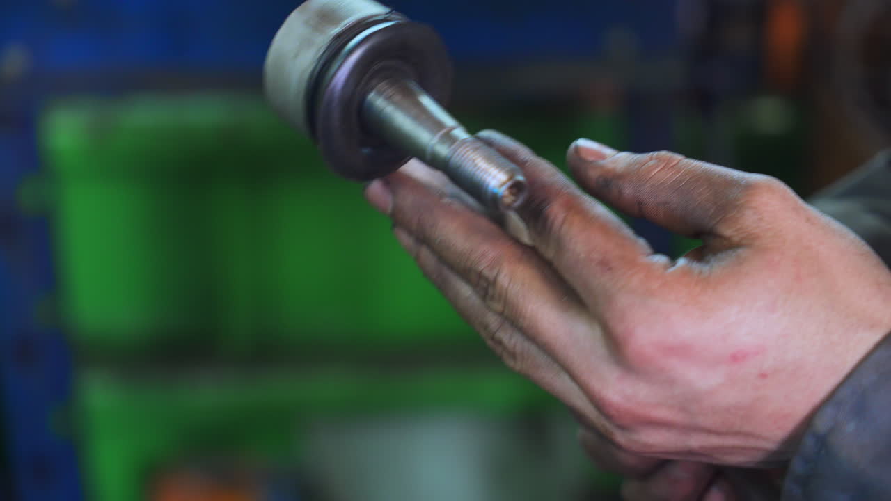 Turner's dirty hands holding a piece of detail. He's turning it and checking. Close up. Blurred background.
