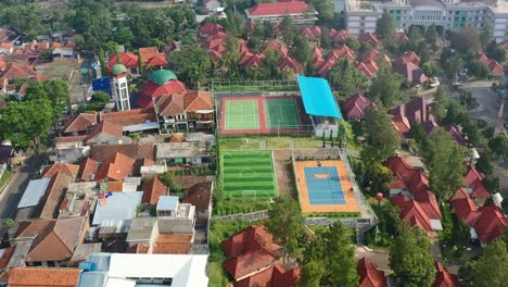 university sports complex with soccer field and tennis courts in bandung indonesia, aerial top down