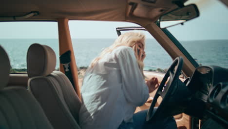 mujer en un coche de época junto al océano