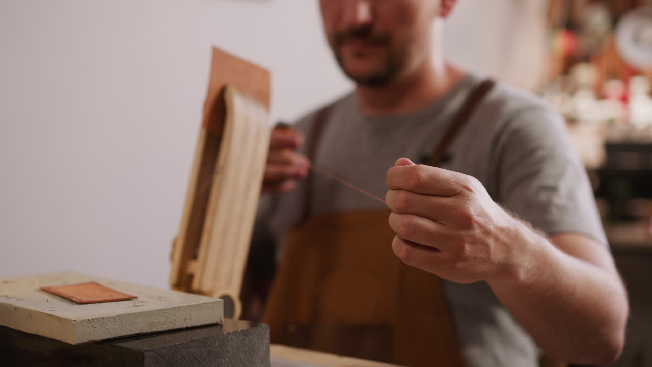Worker pulls waxed thread for leather materials sewing