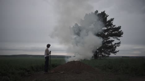 hombre preparando un fuego en un campo al anochecer