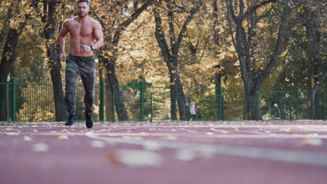 muscular man is training on outdoor stadium. young sportsman without shirt running during his workout on athletics track. healthy lifestyle.