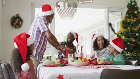 Fröhliche-Afroamerikanische-Familie-Mit-Mehreren-Generationen,-Die-Weihnachtsmützen-Trägt-Und-Das-Feiertagsessen-Feiert