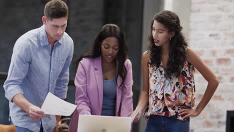 Diverse-male-and-female-colleagues-in-discussion-using-laptop-in-casual-office-meeting,-slow-motion