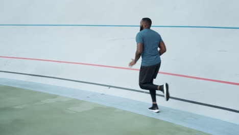 Sporty man running on athletics track