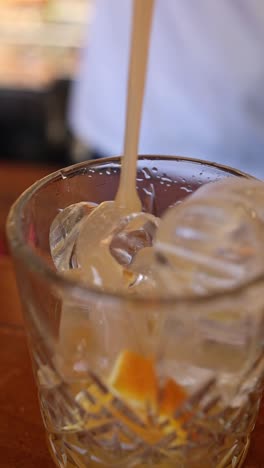 pouring a cocktail with ice and orange slice