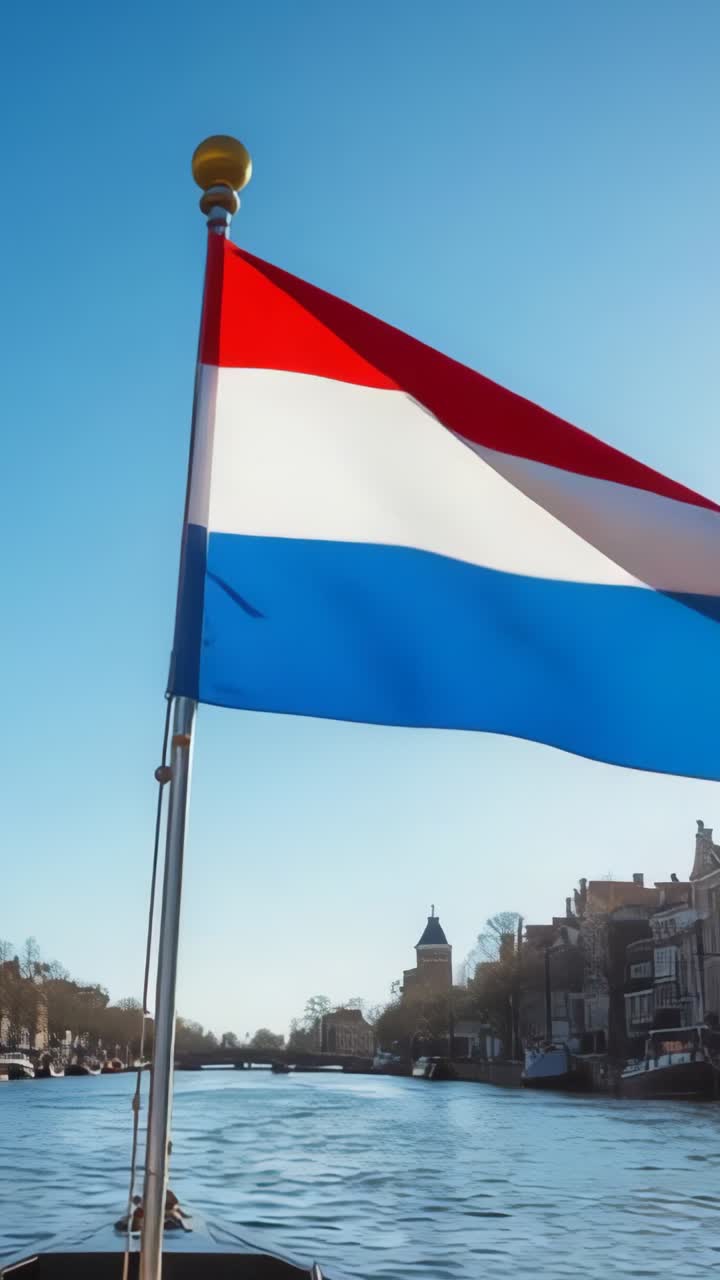 Vertical video: Breeze picking up causing Dutch flag snapping on boat flagpole at canal waterway