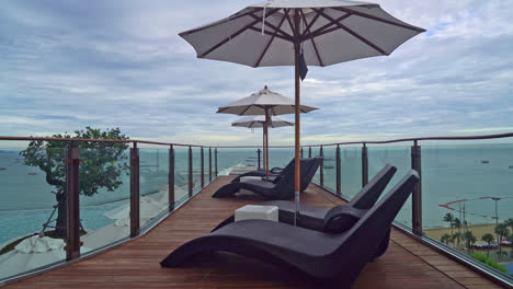 bed pool with umbrella around swimming pool with sea background - holidays and vacation concept