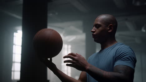 focused man spinning ball on finger. athlete making trick with basketball ball