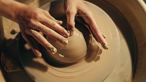 hands shaping clay on a pottery wheel