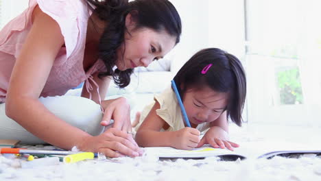 mother looking at her daughter as she colours