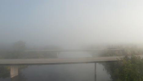 El-Dron-Que-Se-Aleja-De-Los-Puentes-De-Las-Carreteras-Que-Cruzan-Un-Río-Pacífico-Asciende-A-La-Niebla-Que-Se-Cierne-Sobre-El-Paisaje