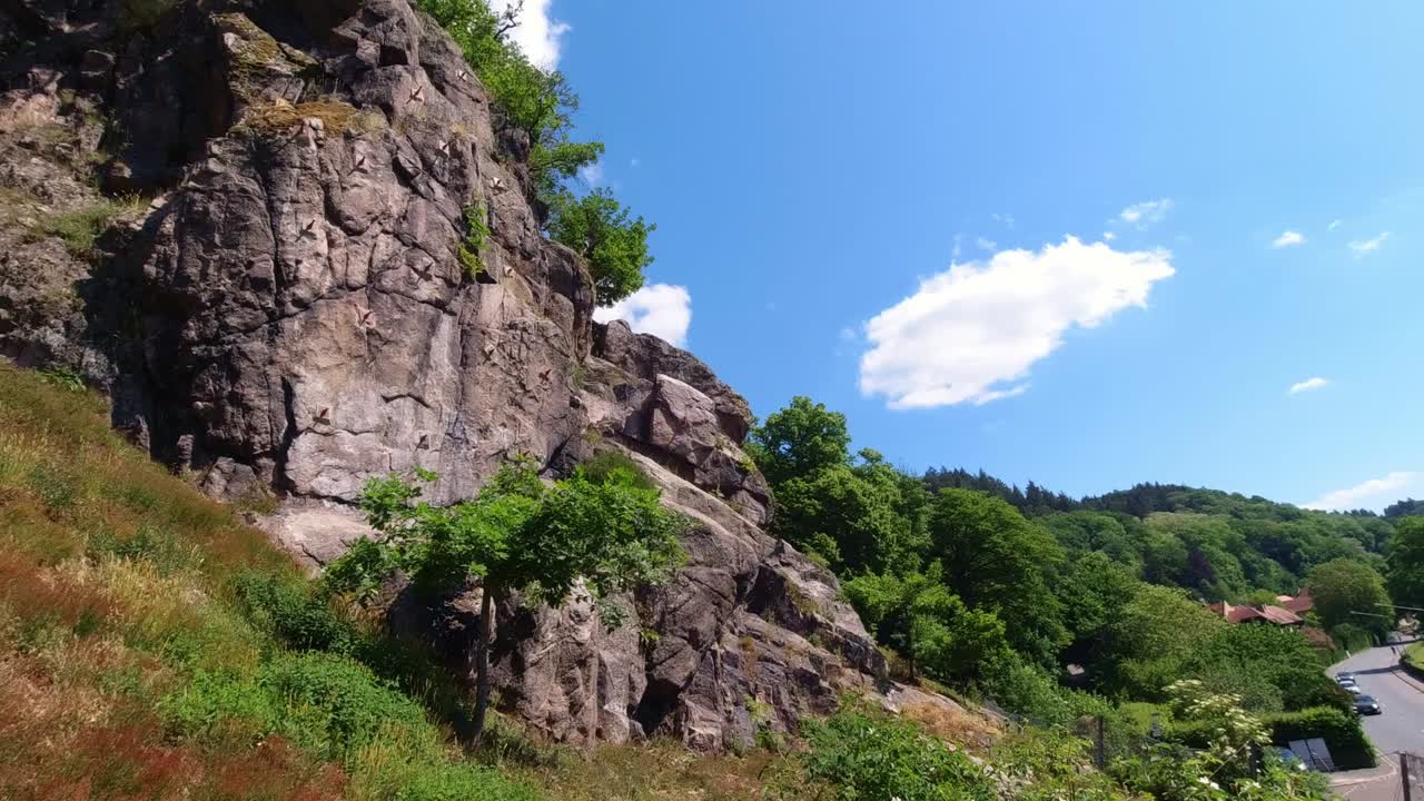Panning view of rock climbing wall near road on spring day, Heidelberg Germany.