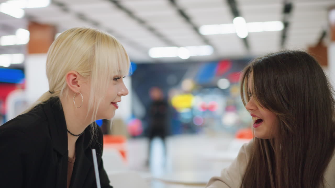 Young lady demonstrates something on tablet to her friend indoors, expressing focus and sharing ideas during casual meeting, highlighting teamwork, technology, and creative interaction