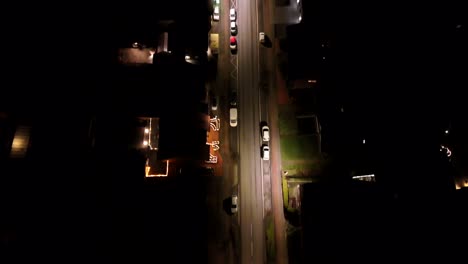cars on road at night with warm lighting lantern and christmas decoration in front yard of house. aerial top down flyover. parking vehicles on street. american suburb neighborhood in connecticut.