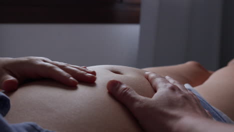primer plano de las manos acariciando suavemente el vientre de la embarazada