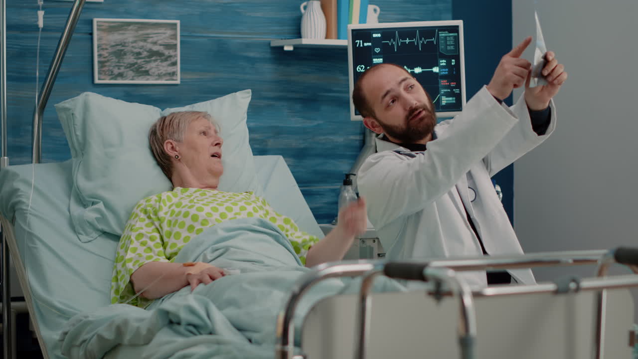 Doctor and elder woman in bed looking at x ray scan