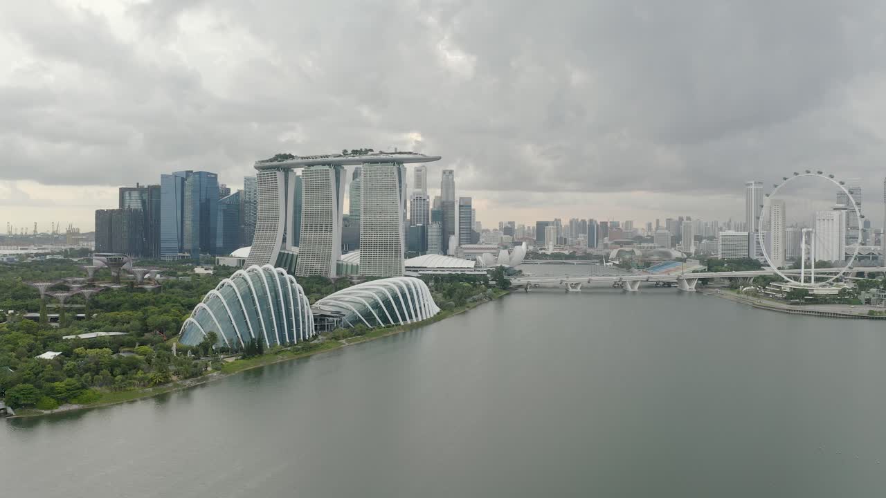 Side flying drone shot of Marina Bay with Gardens by the Bay, Marina Bay Sands, and Singapore Flyer during golden hour (4K).mp4