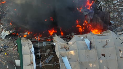 Aerial-top-down-shot-of-burning-fire-with-black-smoke-after-gas-leak-explosion---Establishing-drone-shot