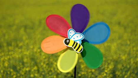 juguete de molino de viento en el campo de colza y imagen de abeja