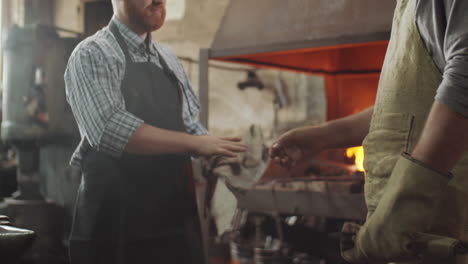 two blacksmiths greeting each other with handshake at work