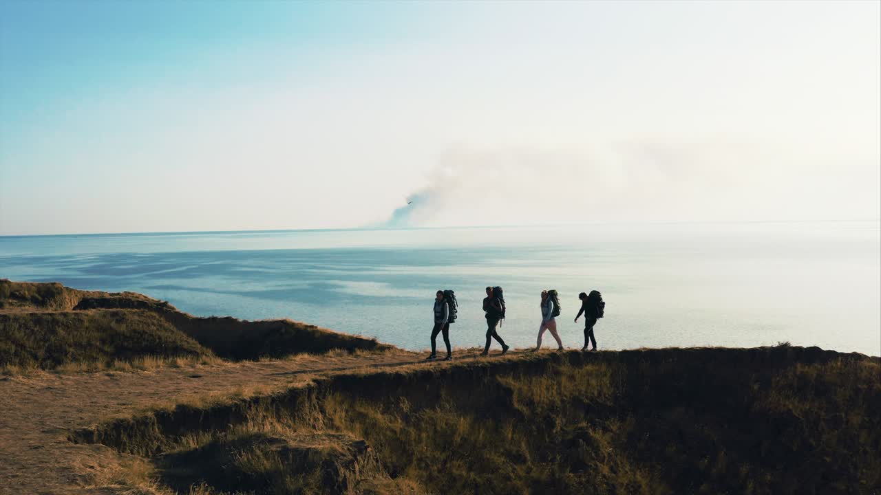 바다 풍경에 대항하여 산에서 고 있는 배을 가진 네 사람