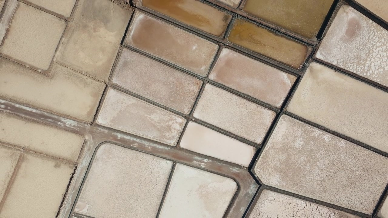 Top-down luftdroneudsigt over Salinas de Janubio saltsletter på Lanzarote, Spanien, der viser geometriske saltbassiner og abstrakte mønstre. Del 1.