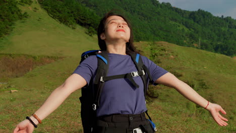 young asiatic female backpackers breathing fresh pure unpolluted air during a mountains trekking slow motion