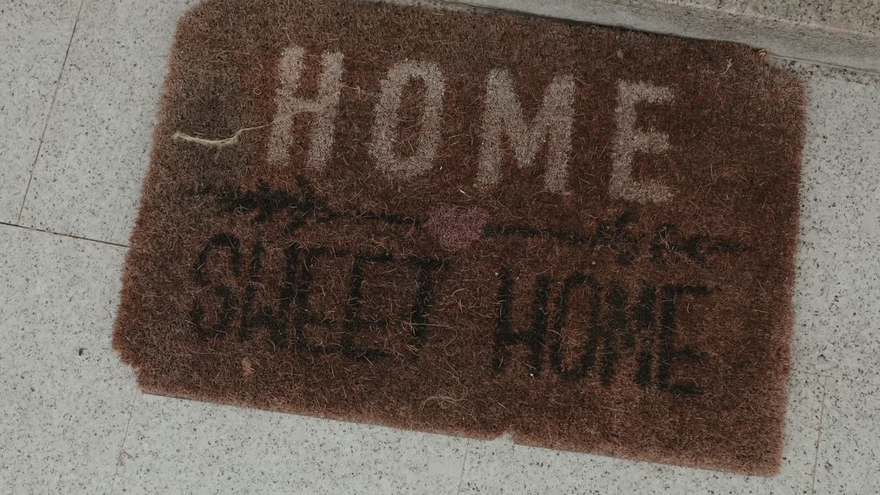 Primo piano di uno zerbino marrone con la scritta "casa dolce casa" all'ingresso di un'abitazione