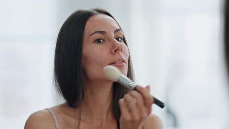 Chica-Enfocada-Empolvándose-La-Cara-Usando-Un-Cepillo-En-El-Primer-Plano-De-Casa.-Mujer-Aplicando-Maquillaje