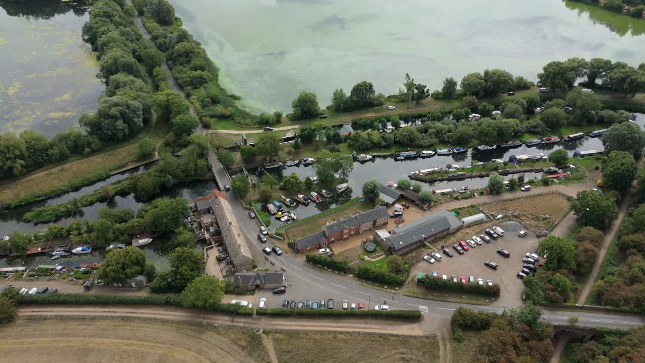 Scenic aerial footage of river and boats through countryside fields and village area Great Addington England UK