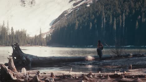 Stunning-reveal-shot-of-a-female-hiker-standing-next-to-a-mountain-lake