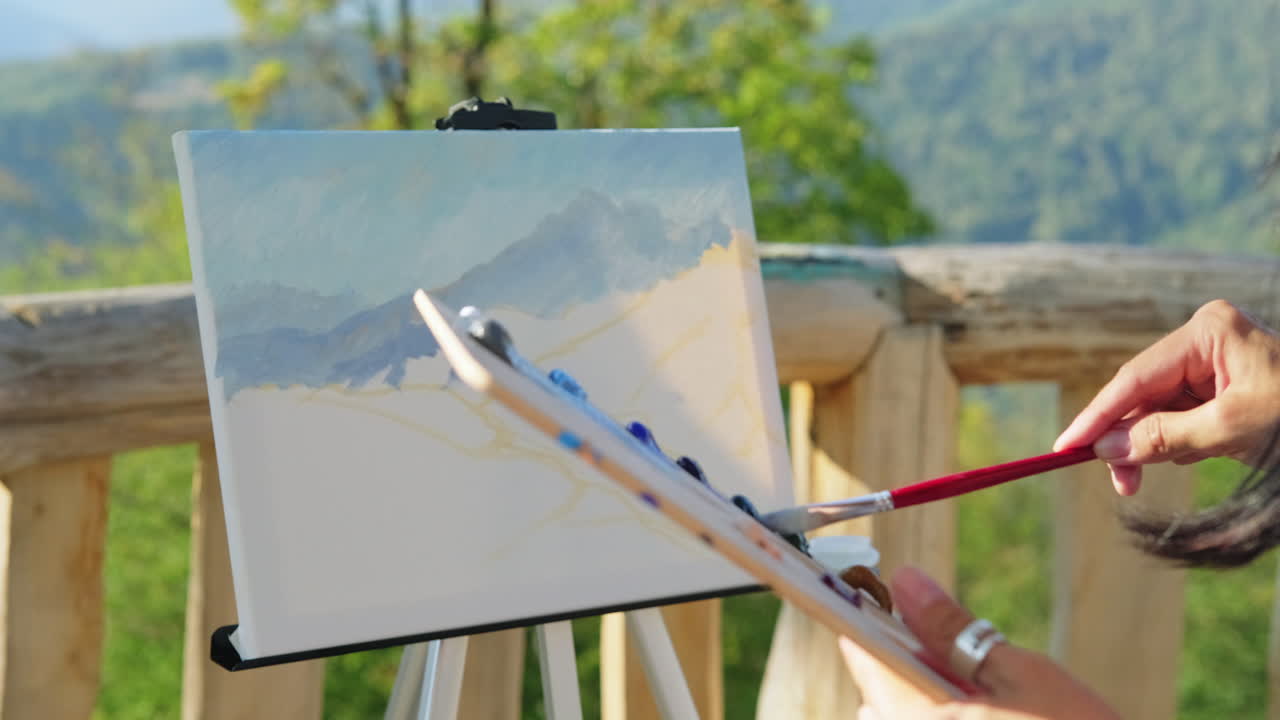 예술가 가 야외 에서 산의 풍경 을 그린다