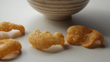 beaautiful ceramic bowl with pattern on white table containing orange reddish crisps.