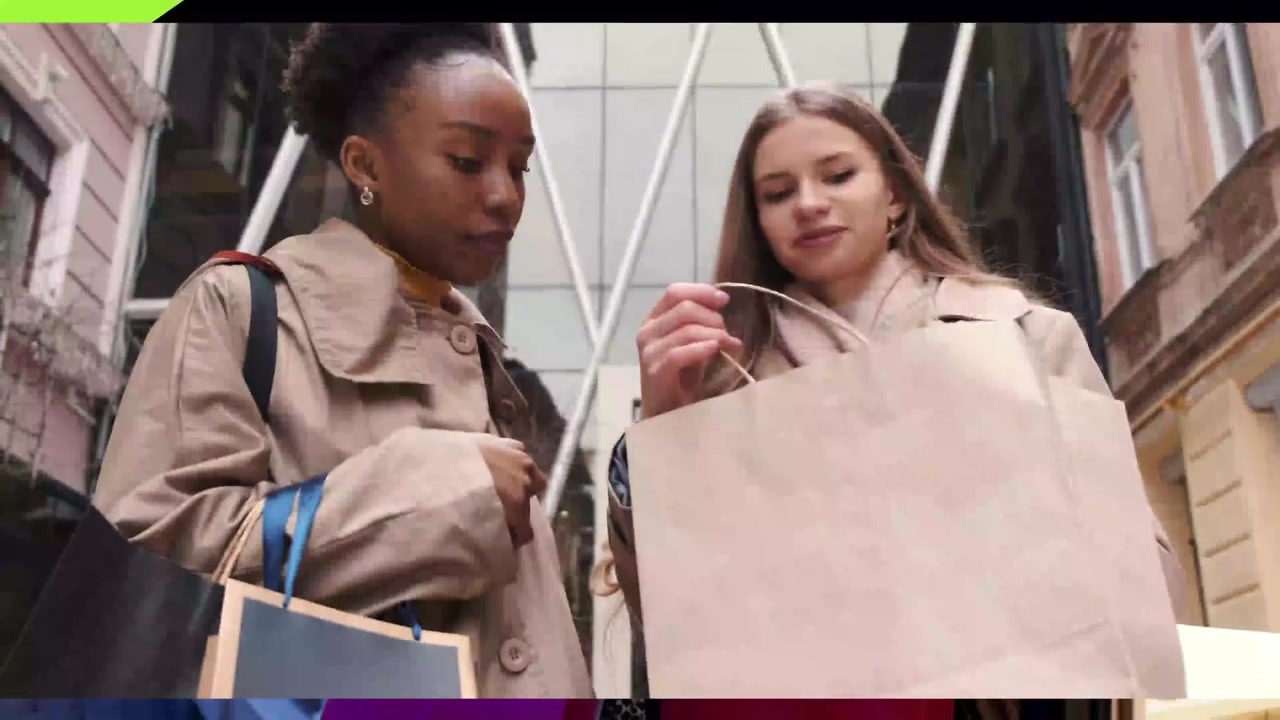 Deux jeunes femmes regardant dans un sac de shopping dans une rue de la ville