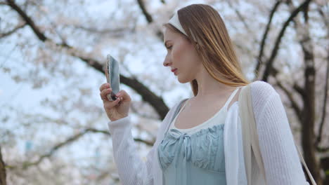 portrait of a blonde young woman using mobile phone at yangjae citizen's forest park in seocho district, seoul city, south korea