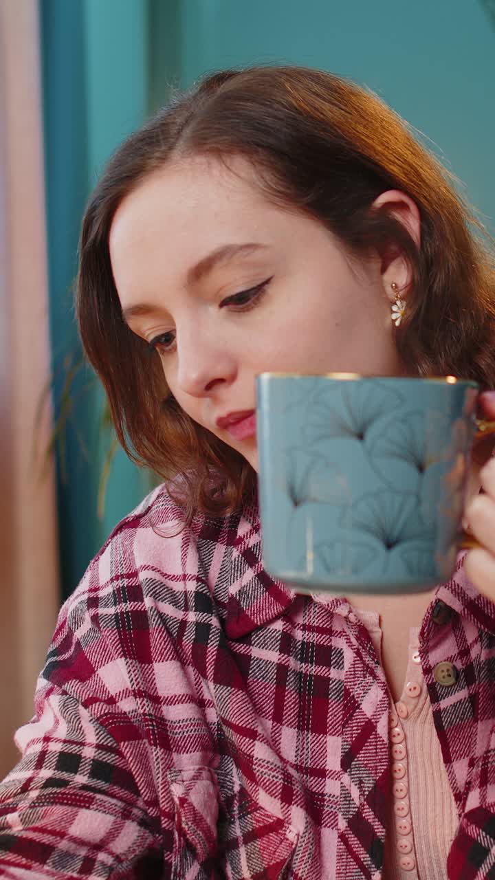 mujer de negocios trabajando en una computadora portátil bebiendo una taza de café caliente caliente sentada en la mesa en la oficina de casa