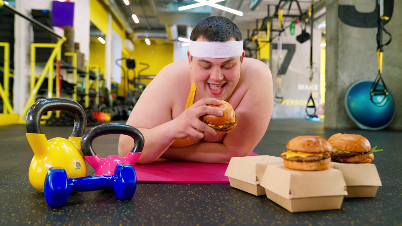 Uomo sovrappeso in palestra tentato dagli hamburger