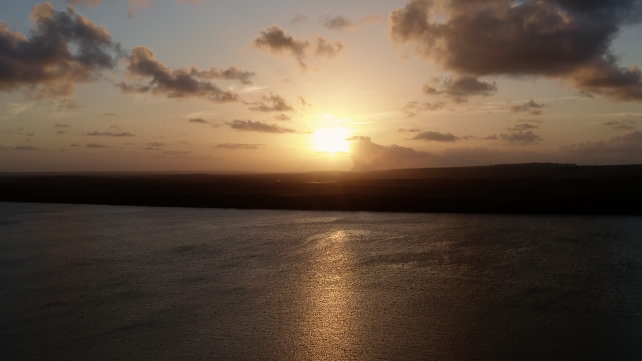 Rising aerial drone shot of a stunning golden sunset from the famous tourist destination alligator beach at a large river in Cabedelo, Paraiba, Brazil near the coastal capital city of Joao Pessoa