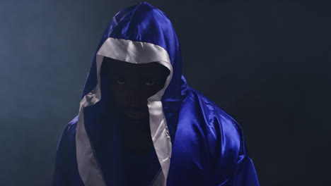 Portrait-Of-Boxer-Wearing-Robe-Entering-Ring-Before-Start-Of-Boxing-Match-With-Low-Key-Lighting