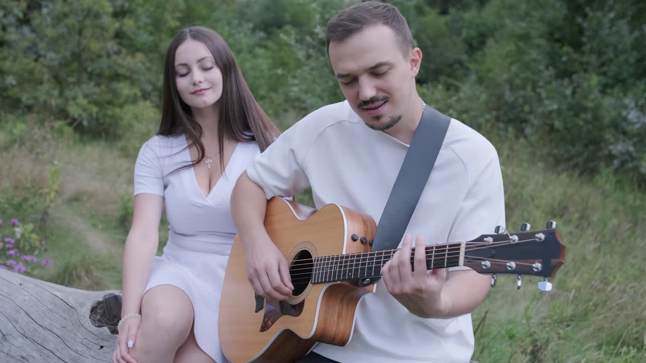 A couple enjoying music with an acoustic guitar outdoors