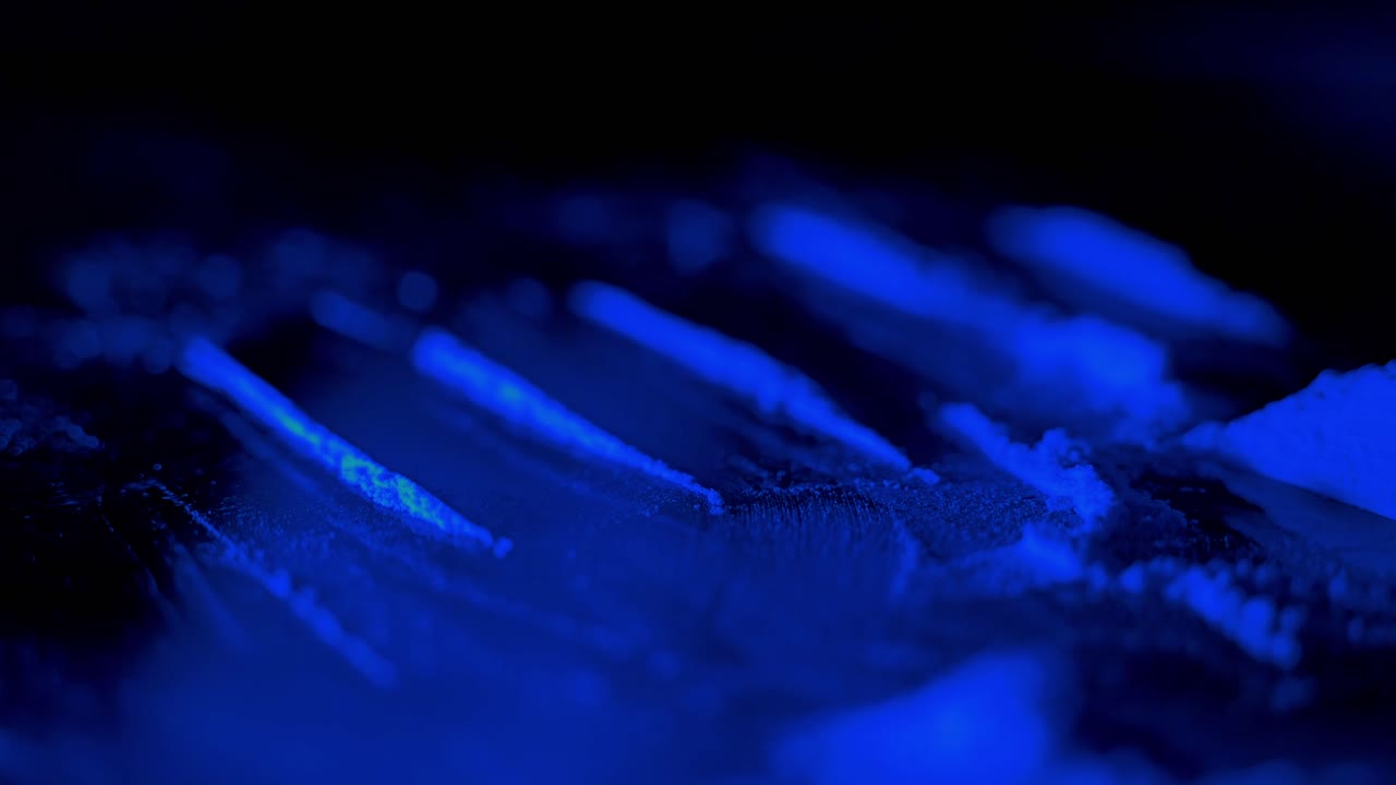 Close up macro shot of white drug powder lines prepared under blue neon light