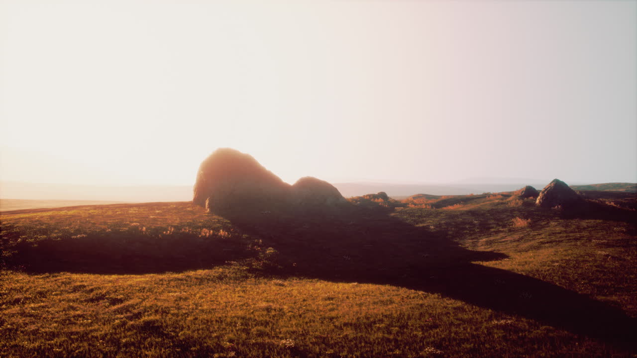 바위 와 함께 잔디 언덕 위 에 해가 뜨는 것