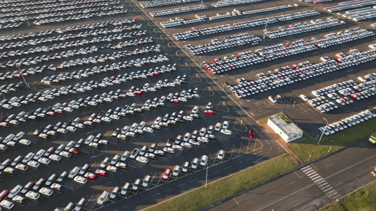 Aerial tilt down over mass storage parking lot with brand new vehicles