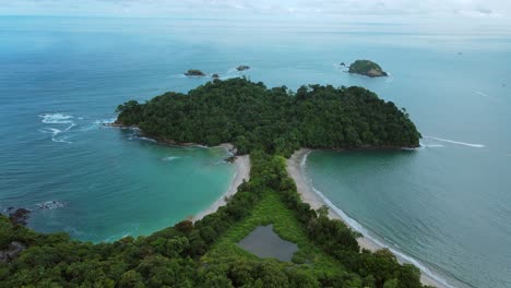 Toma-Aérea-De-Una-Playa-Con-Forma-De-Cola-De-Ballena-En-El-Parque-Nacional-Manuel-Antonio,-Costa-Rica