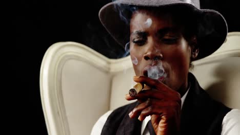 androgynous man smoking cigar on armchair